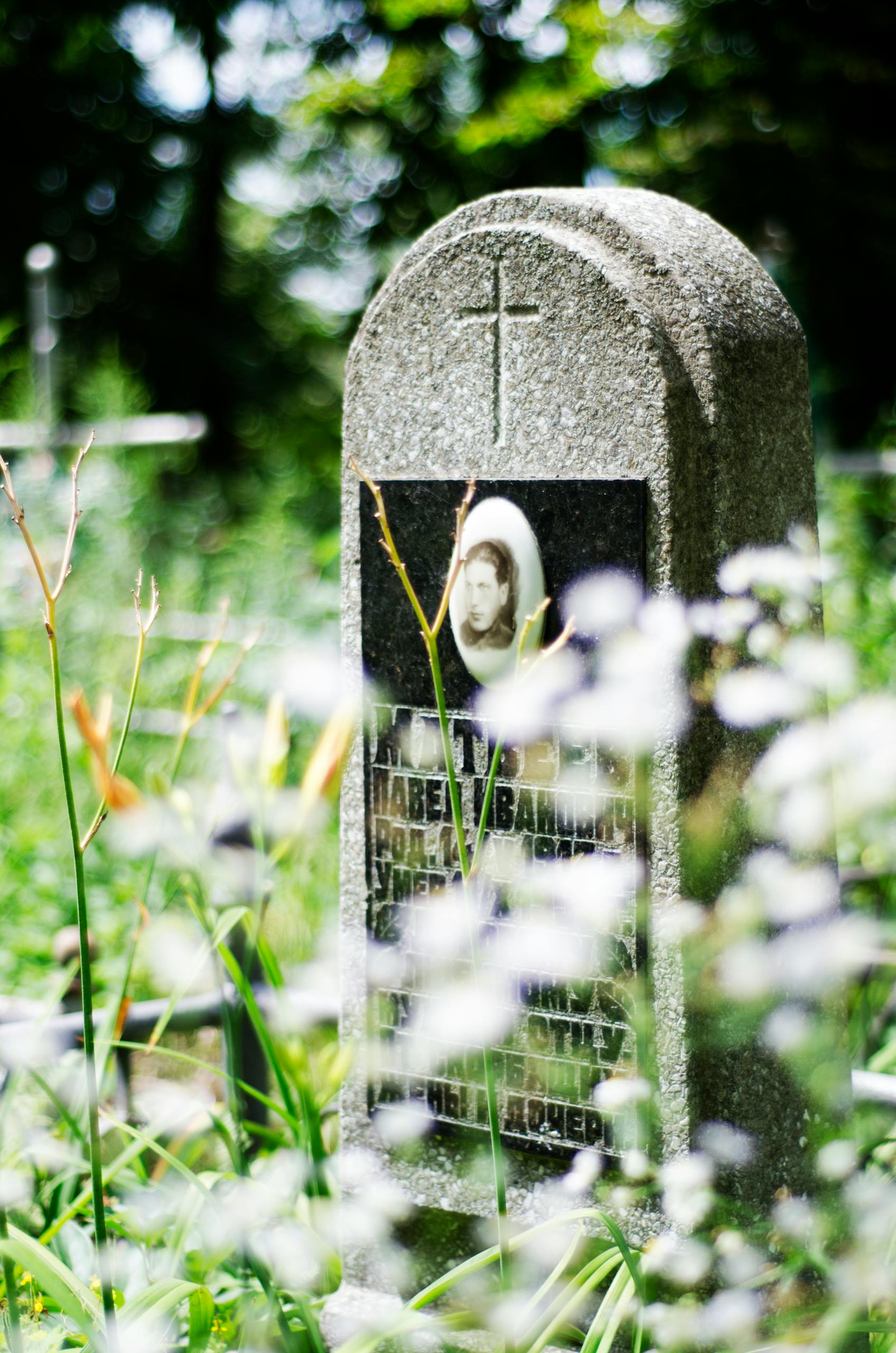 A tranquil cemetery scene with an ornate gravestone surrounded by wildflowers, evoking peace and reflection.
